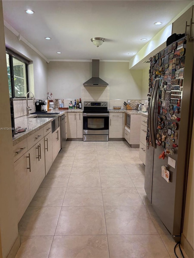 kitchen with sink, light stone counters, wall chimney exhaust hood, ornamental molding, and appliances with stainless steel finishes