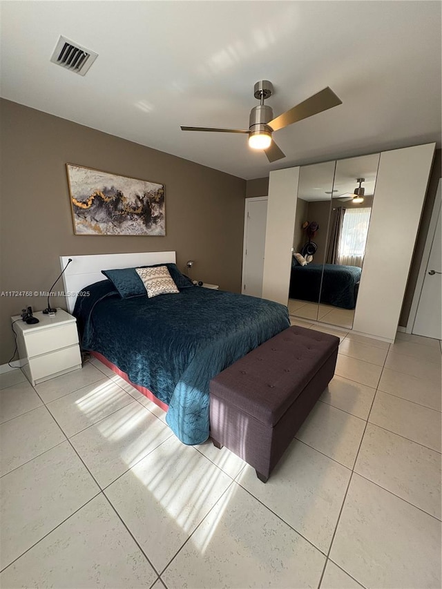 bedroom with ceiling fan, tile patterned floors, and a closet