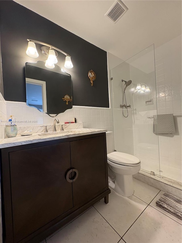 bathroom featuring toilet, walk in shower, vanity, tile patterned floors, and tile walls