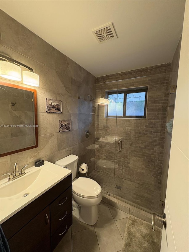 bathroom featuring tile patterned flooring, toilet, vanity, tile walls, and an enclosed shower