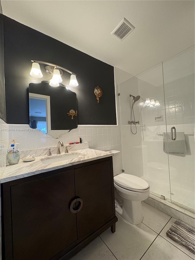 bathroom featuring toilet, walk in shower, vanity, tile patterned floors, and tile walls