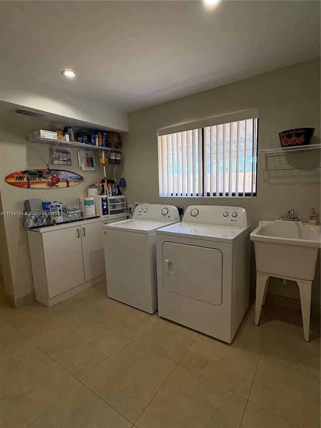 clothes washing area featuring washing machine and clothes dryer, light tile patterned floors, and sink