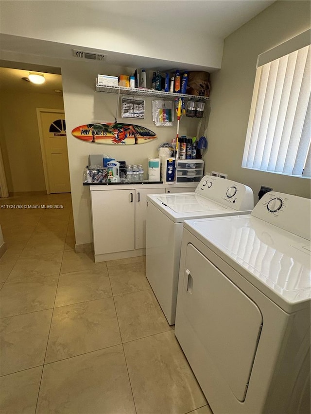 laundry room featuring light tile patterned flooring, cabinets, and washing machine and clothes dryer