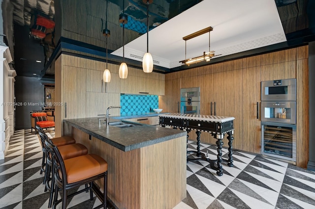 kitchen featuring wine cooler, dark countertops, light floors, a kitchen bar, and a sink
