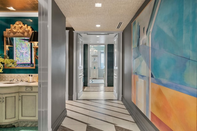 hallway with baseboards and a sink