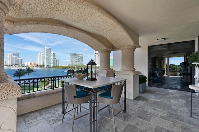 view of patio / terrace featuring a water view, a city view, and a balcony