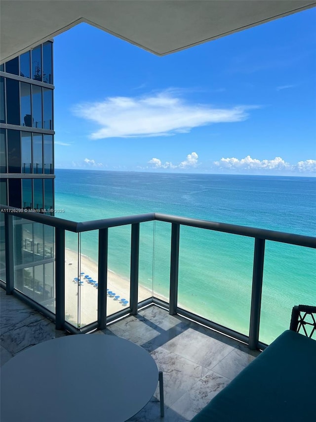 balcony with a water view and a view of the beach