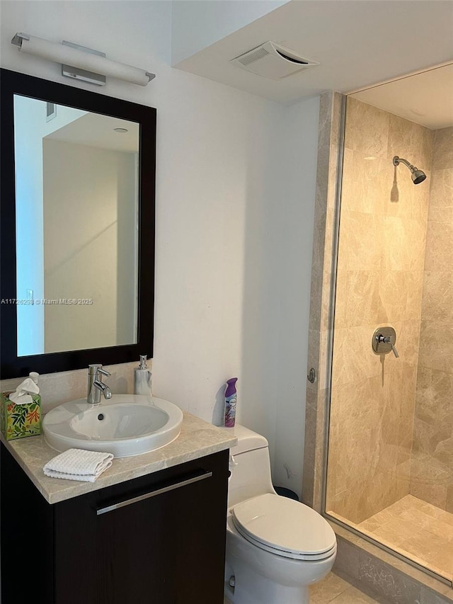 bathroom featuring toilet, tile patterned floors, tiled shower, and vanity