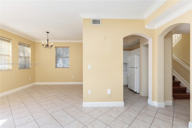 tiled spare room with ornamental molding and an inviting chandelier