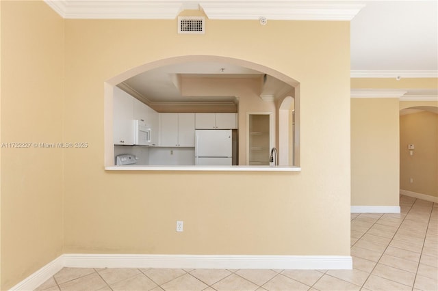 unfurnished room with sink, crown molding, and light tile patterned floors