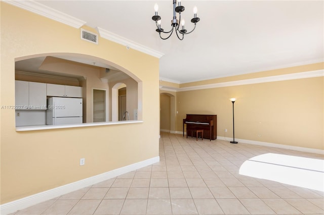 spare room featuring ornamental molding, a notable chandelier, and light tile patterned floors