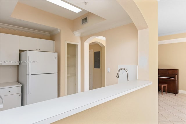 kitchen with white fridge, electric panel, light tile patterned floors, white cabinets, and sink