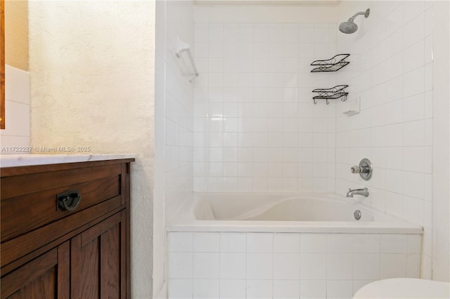 full bathroom with toilet, vanity, and tiled shower / bath