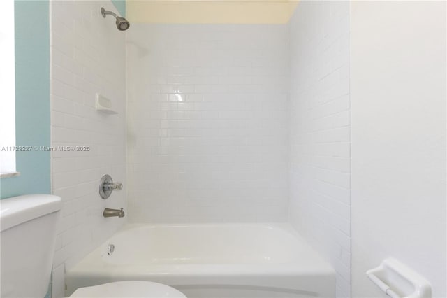 bathroom with tiled shower / bath combo and toilet