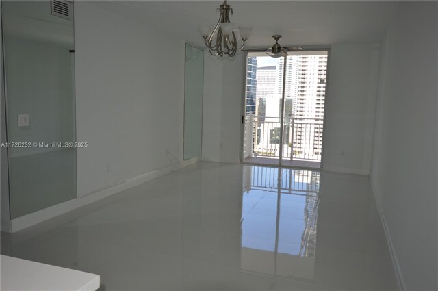 spare room with tile patterned flooring, floor to ceiling windows, and a chandelier