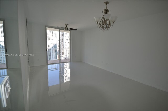 spare room with ceiling fan with notable chandelier and floor to ceiling windows