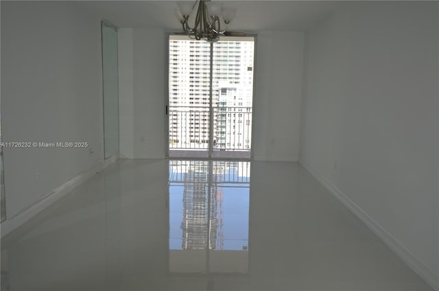 spare room featuring tile patterned flooring, floor to ceiling windows, and a notable chandelier