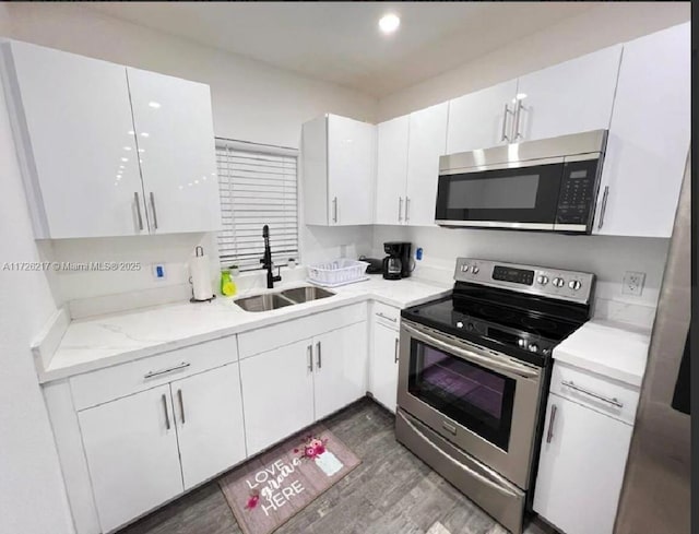 kitchen featuring sink, white cabinets, light stone countertops, dark hardwood / wood-style flooring, and appliances with stainless steel finishes