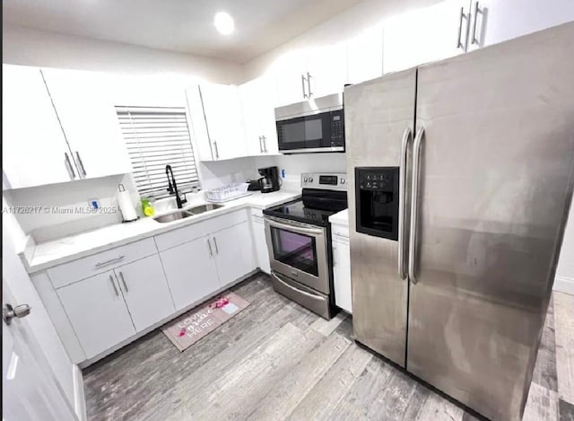 kitchen featuring sink, white cabinetry, light hardwood / wood-style floors, and appliances with stainless steel finishes