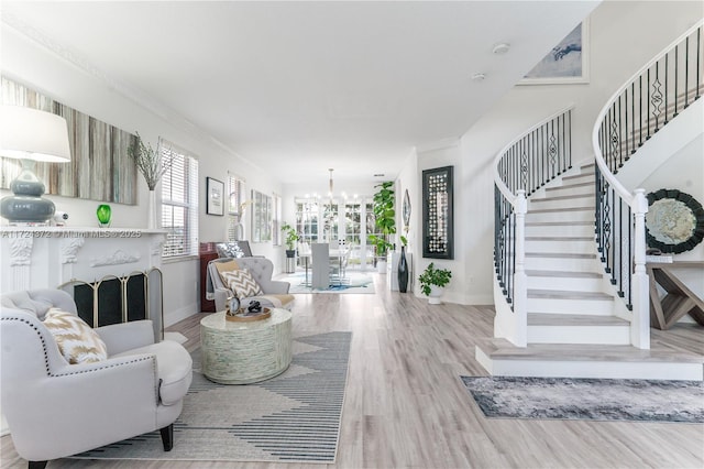 living room featuring an inviting chandelier, ornamental molding, and light hardwood / wood-style floors