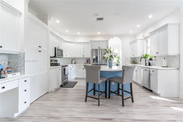 kitchen featuring light hardwood / wood-style flooring, a kitchen island, white cabinetry, appliances with stainless steel finishes, and a kitchen breakfast bar