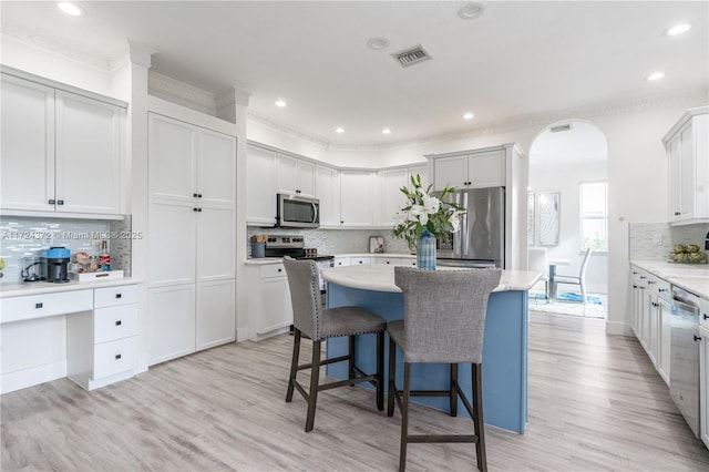 kitchen with stainless steel appliances, white cabinetry, light wood-type flooring, and a center island