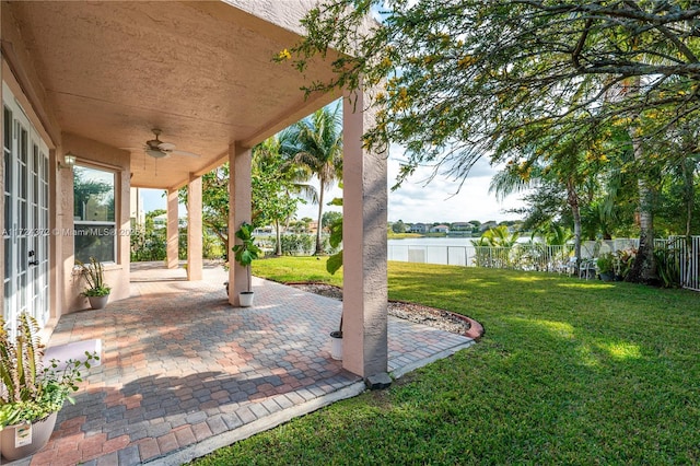 view of yard with ceiling fan, a water view, and a patio area