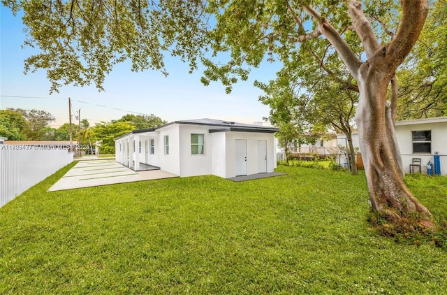 rear view of property featuring a patio and a lawn