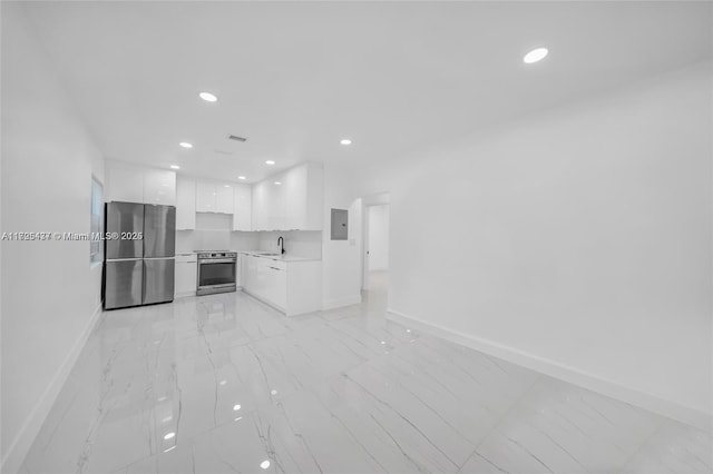 kitchen with sink, white cabinets, electric panel, stove, and stainless steel fridge