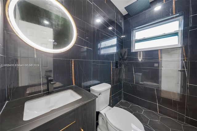 bathroom featuring tile walls, toilet, a tile shower, and vanity