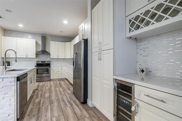 kitchen featuring appliances with stainless steel finishes, backsplash, wine cooler, wall chimney range hood, and sink