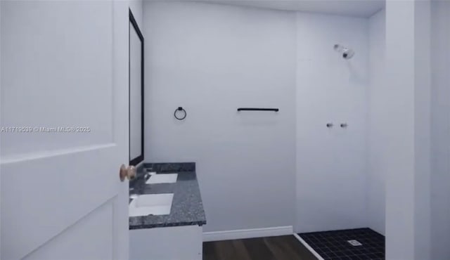 bathroom featuring hardwood / wood-style flooring, tiled shower, and vanity