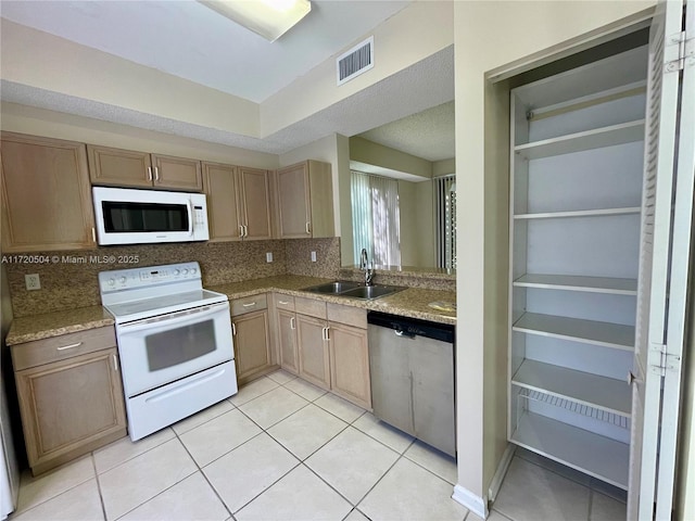 kitchen featuring white appliances, light stone countertops, light tile patterned floors, decorative backsplash, and sink