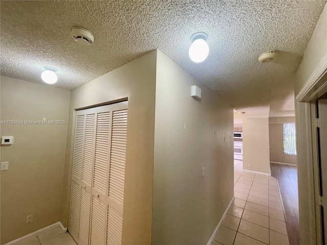 hall featuring a textured ceiling and light tile patterned flooring