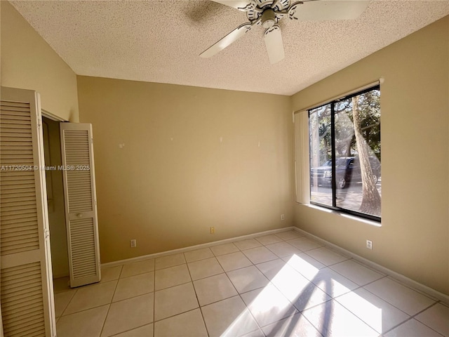 unfurnished bedroom featuring light tile patterned flooring, a closet, ceiling fan, and a textured ceiling