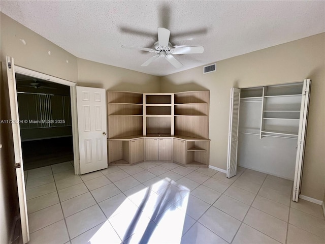 unfurnished bedroom with a textured ceiling, a closet, ceiling fan, and light tile patterned floors