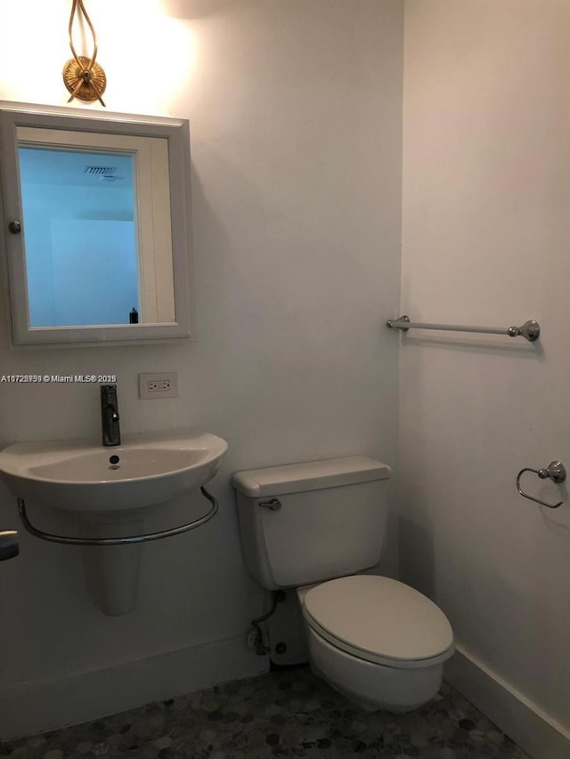 half bath featuring baseboards, a sink, and toilet