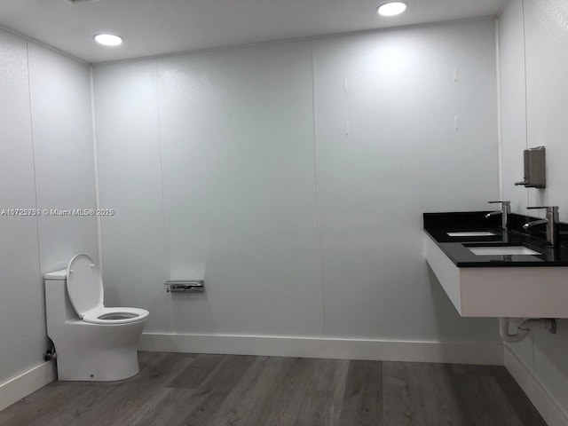 bathroom featuring a sink, wood finished floors, toilet, and recessed lighting