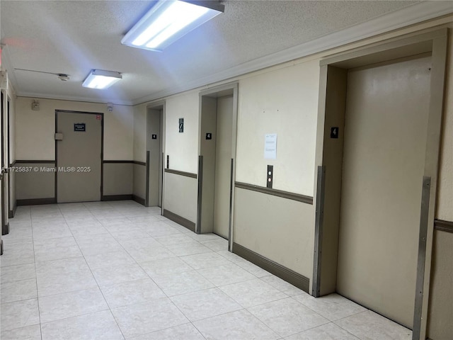 empty room featuring elevator, a textured ceiling, and crown molding