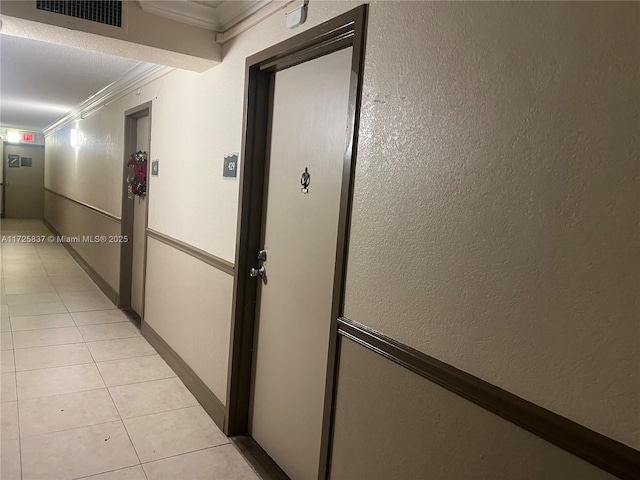 hallway with ornamental molding and light tile patterned flooring