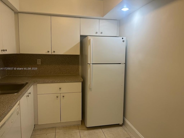 kitchen with sink, white appliances, light tile patterned floors, and white cabinets