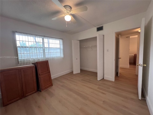 unfurnished bedroom with a textured ceiling, ceiling fan, light hardwood / wood-style flooring, and a closet