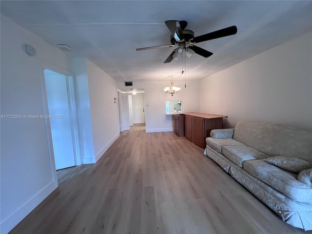 unfurnished living room featuring ceiling fan with notable chandelier and light hardwood / wood-style flooring