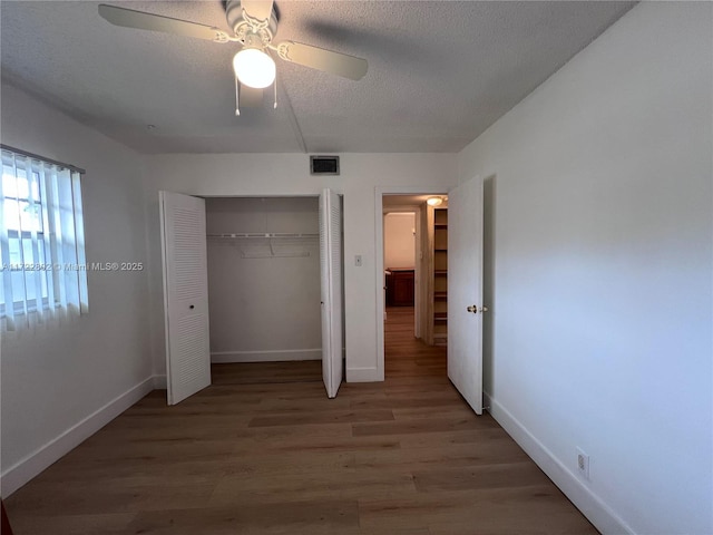 unfurnished bedroom with hardwood / wood-style flooring, a textured ceiling, ceiling fan, and a closet