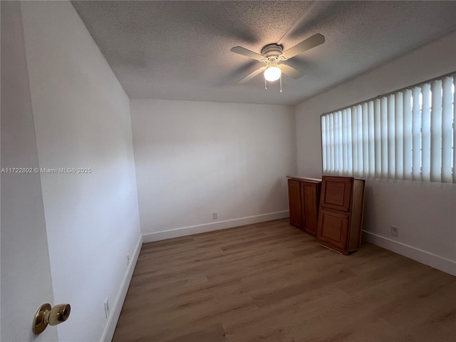 empty room featuring a textured ceiling, ceiling fan, and light hardwood / wood-style floors