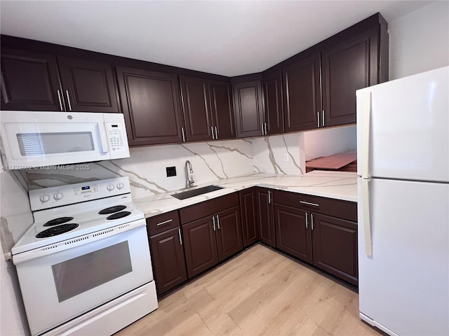 kitchen with white appliances, light wood-type flooring, dark brown cabinets, and sink