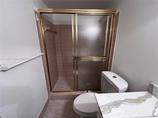 bathroom featuring toilet, tile patterned flooring, and a shower with shower door