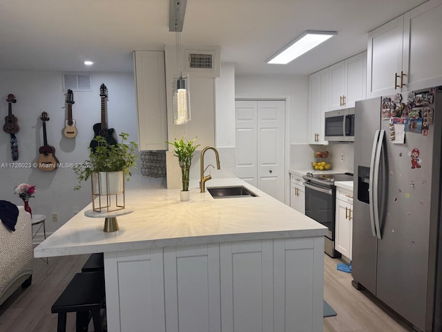 kitchen with sink, white cabinetry, hanging light fixtures, and appliances with stainless steel finishes