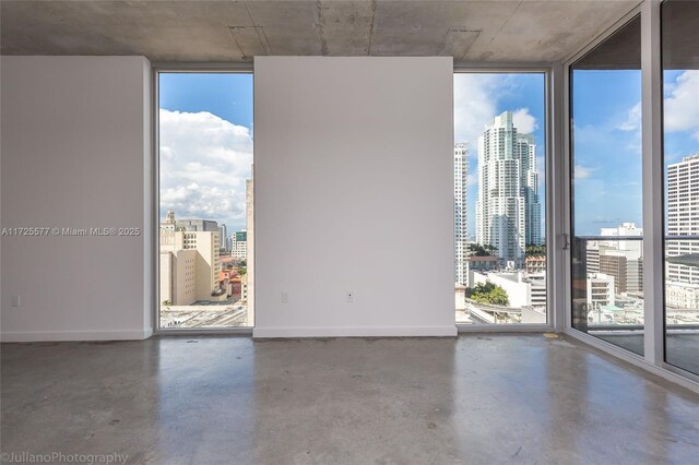 kitchen featuring stainless steel appliances, sink, expansive windows, dark brown cabinetry, and concrete floors