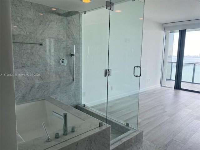 bathroom featuring a wall of windows and independent shower and bath